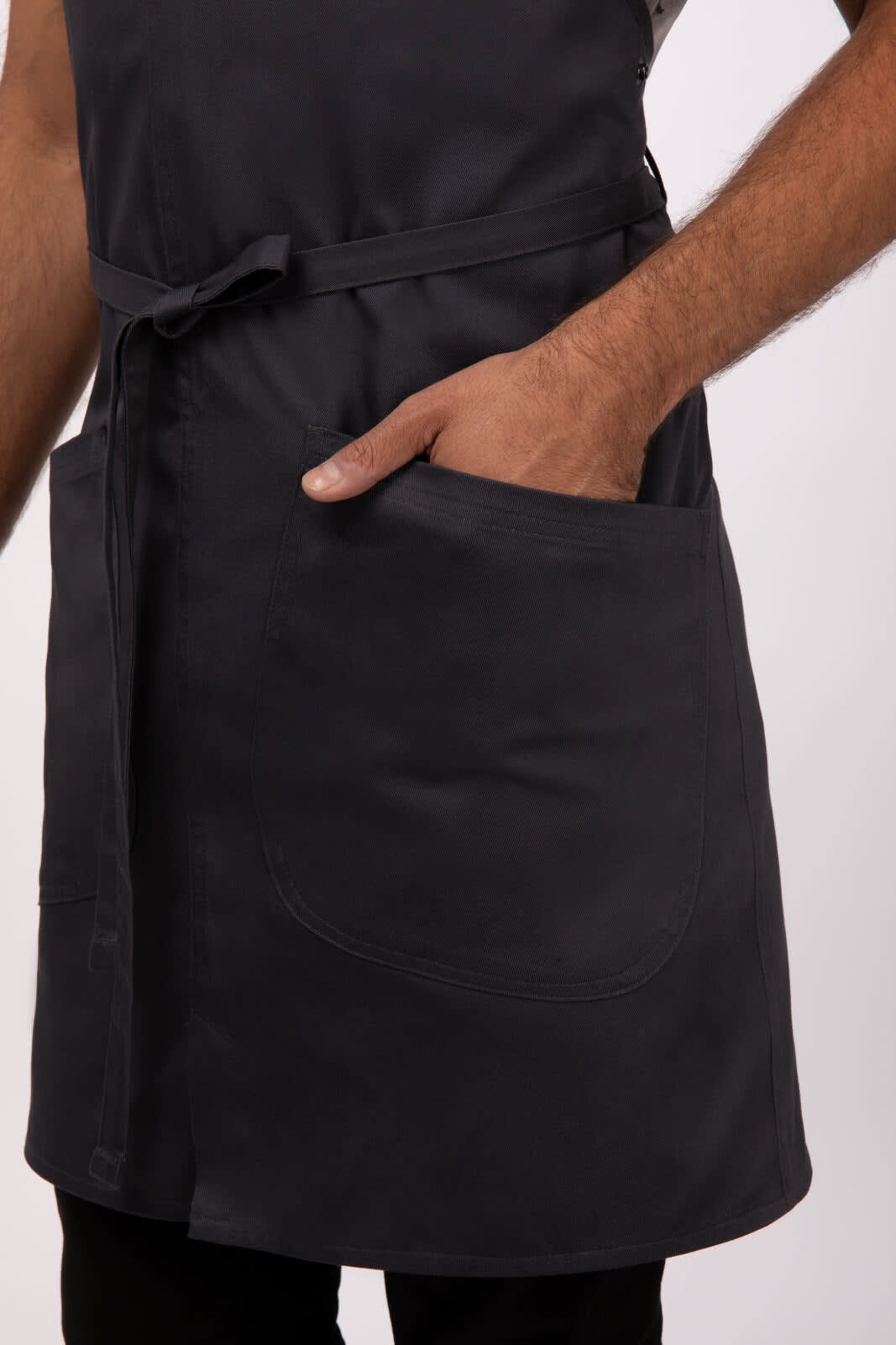 A dark grey bib apron with a pocket, featuring a tie waist and a simple design. It has a logo present.