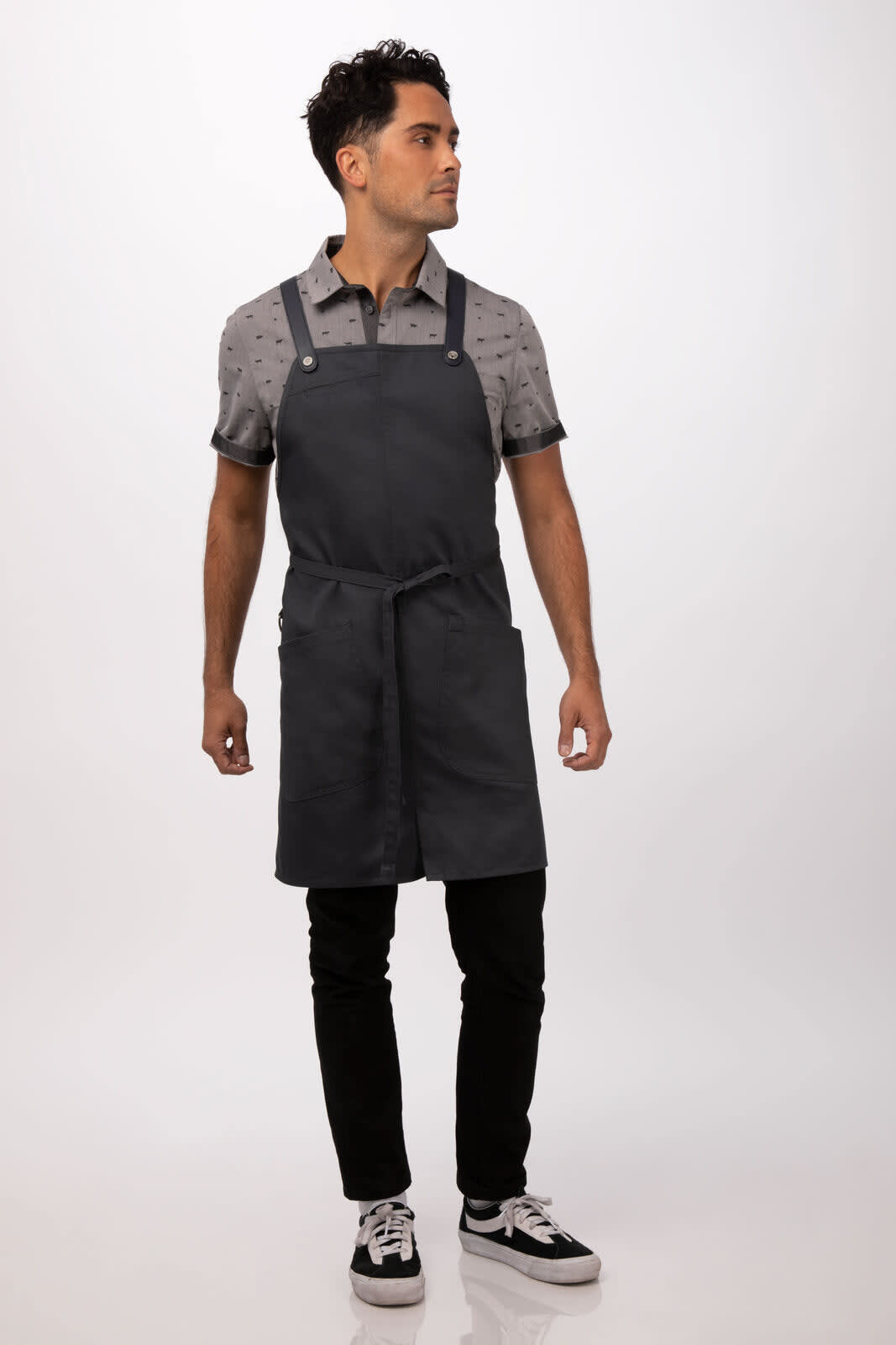 A man wearing a charcoal grey Largo Bib Apron, styled with a patterned shirt and black pants, showcasing a minimalist design.