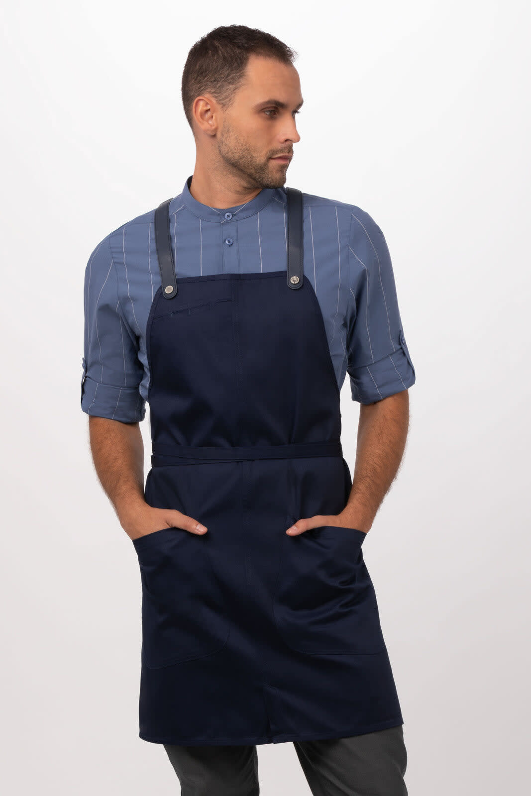 A navy blue bib apron featuring two front pockets and adjustable straps, worn by a model.