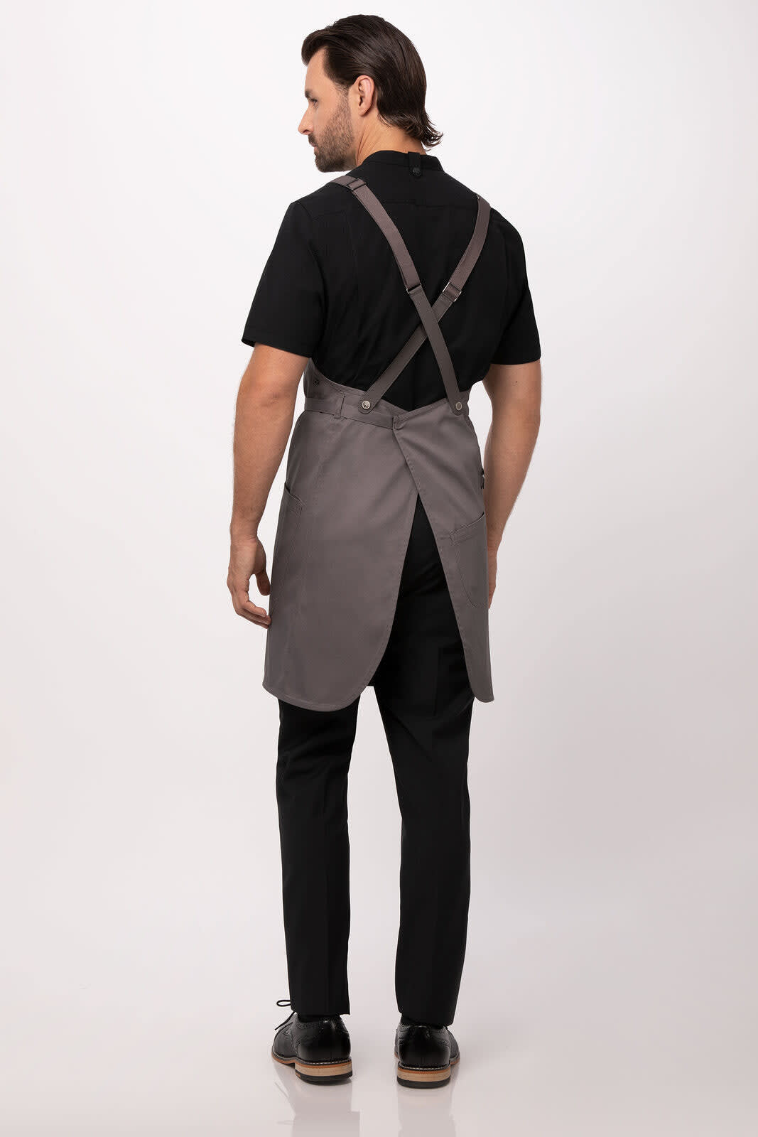 A grey Largo Bib Apron with cross-back straps, worn by a person from the back. The outfit includes a black top and trousers.