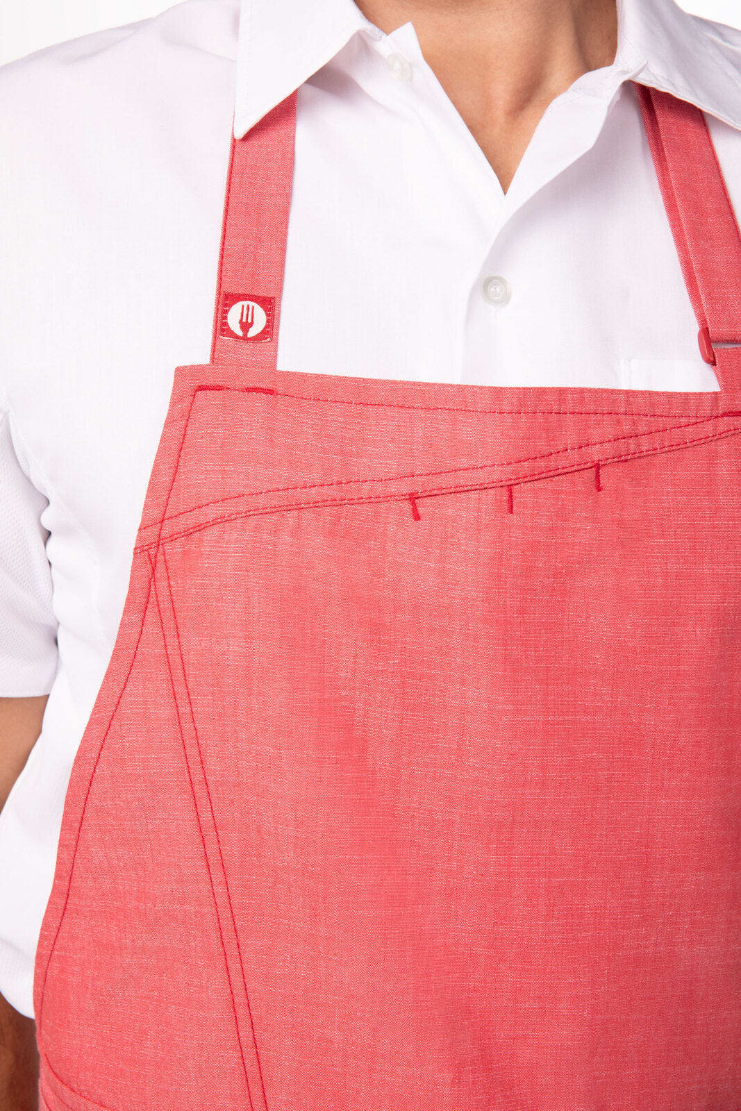 A red Medford Bib Apron featuring adjustable straps and a logo, worn over a white shirt.