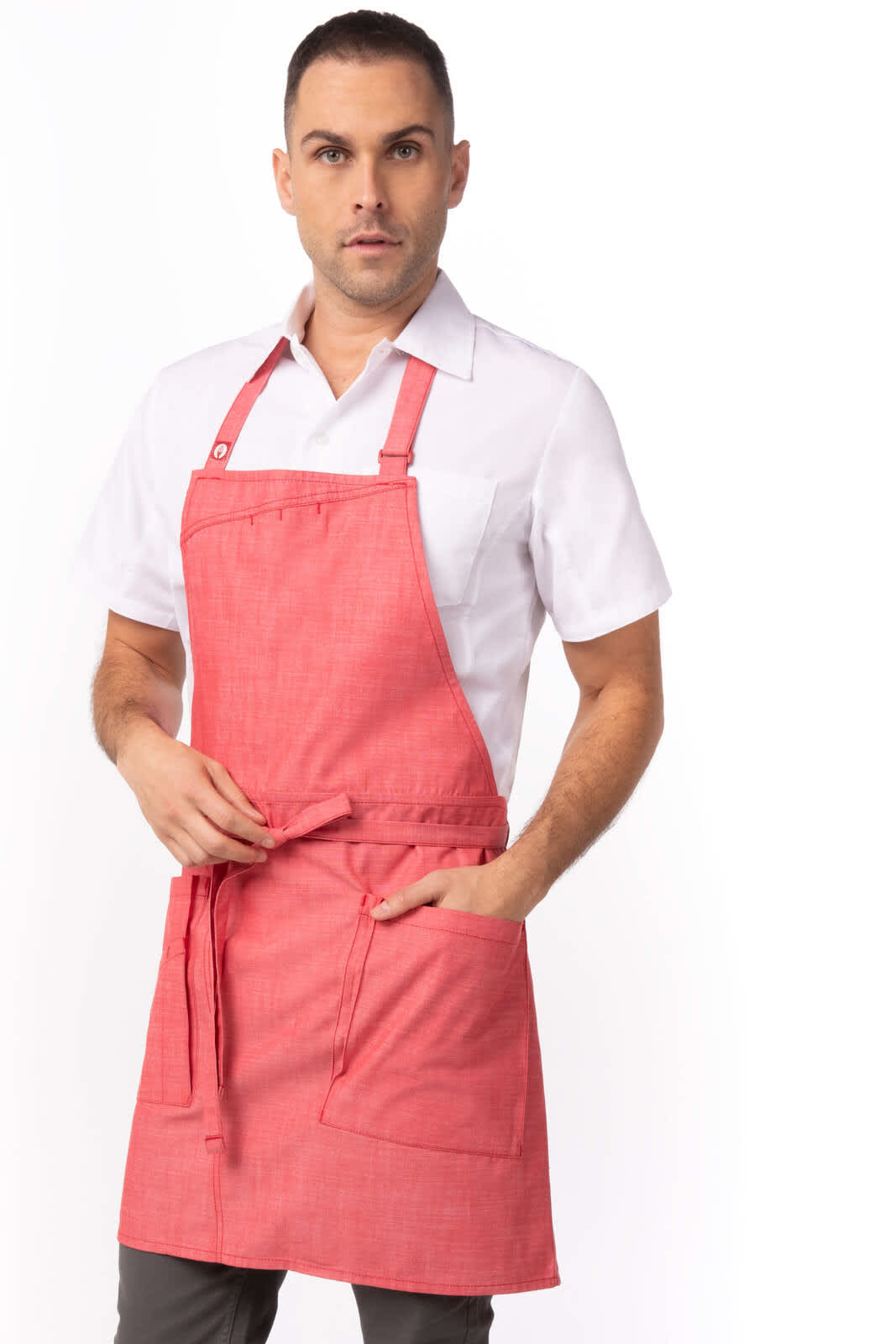 A red bib apron featuring two front pockets and adjustable straps, worn over a white shirt by a male model.