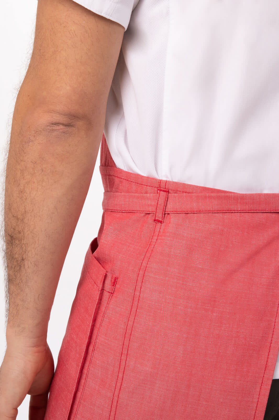 A red Medford Bib Apron featuring a side pocket and a waist tie, positioned on a model's side.