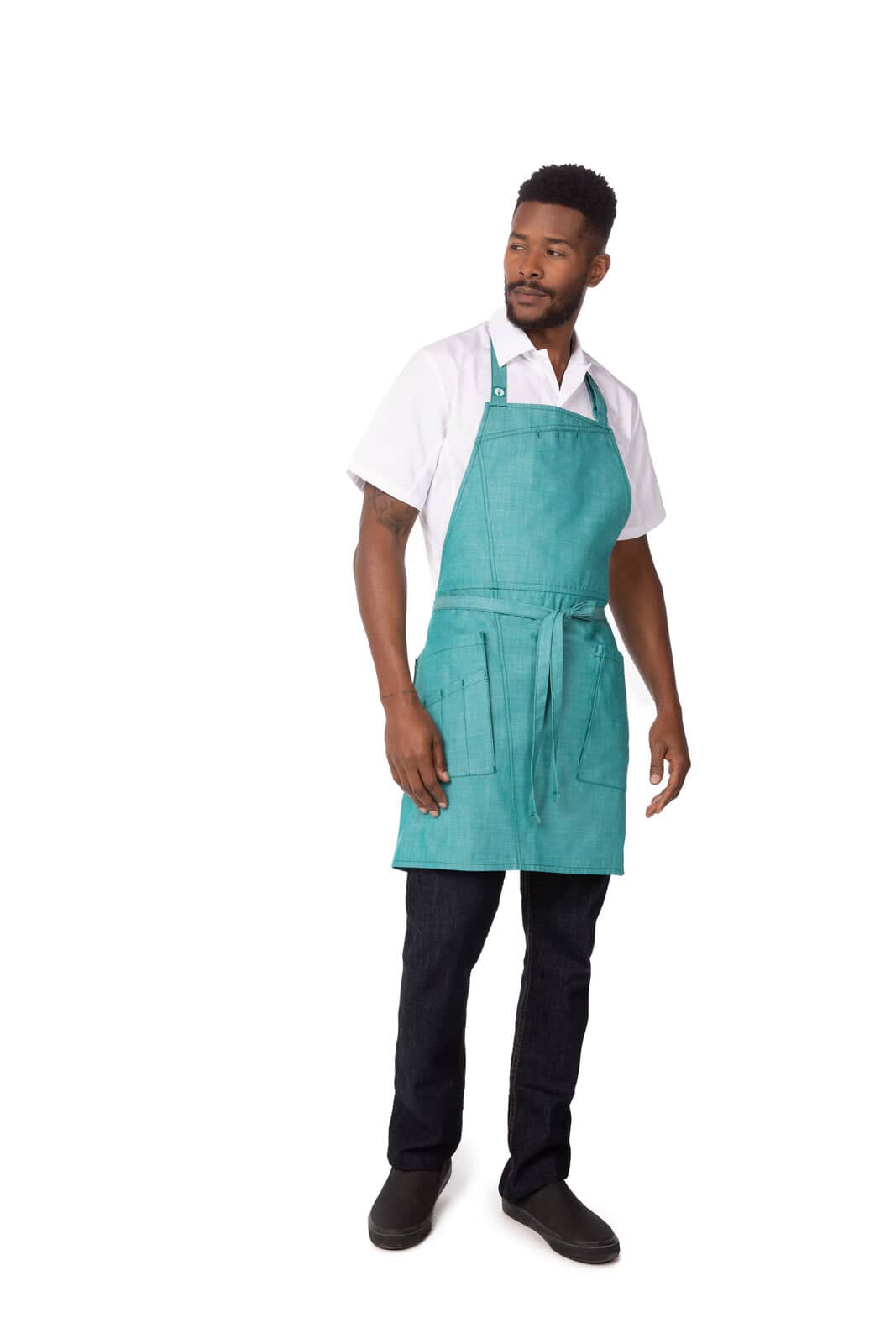 A teal bib apron worn by a man standing, featuring pockets and adjustable straps.