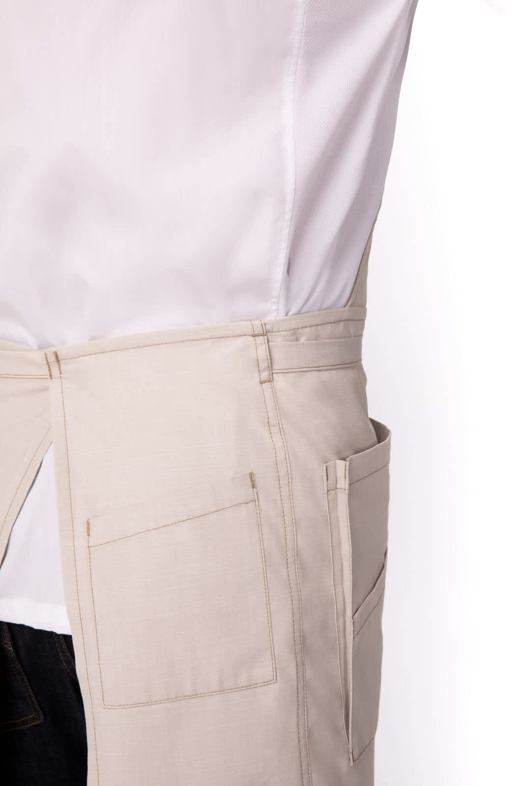 A beige bib apron featuring pockets, designed for workwear, shown from the side.