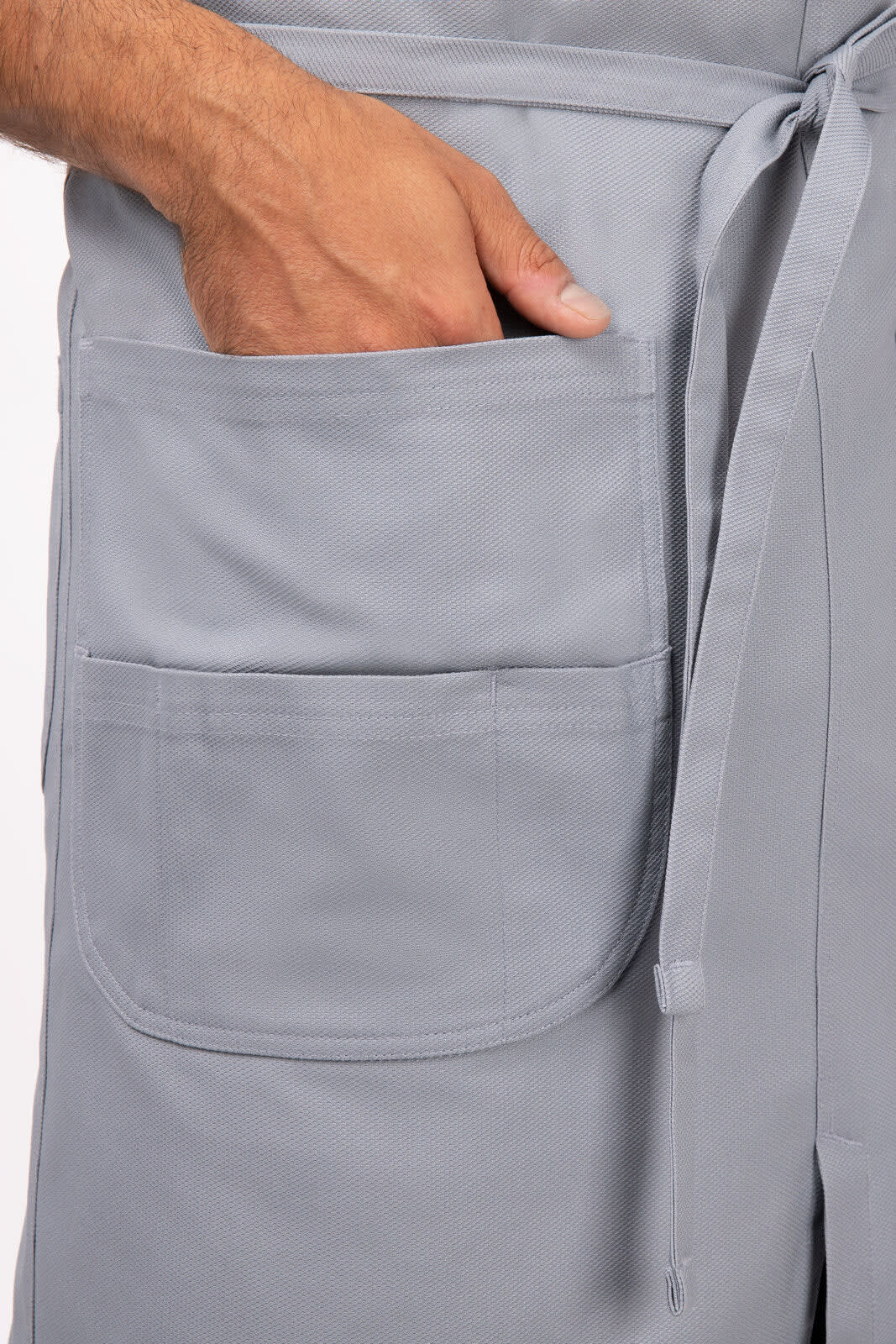 A grey Logan Bib Apron featuring two front pockets and a waist tie.