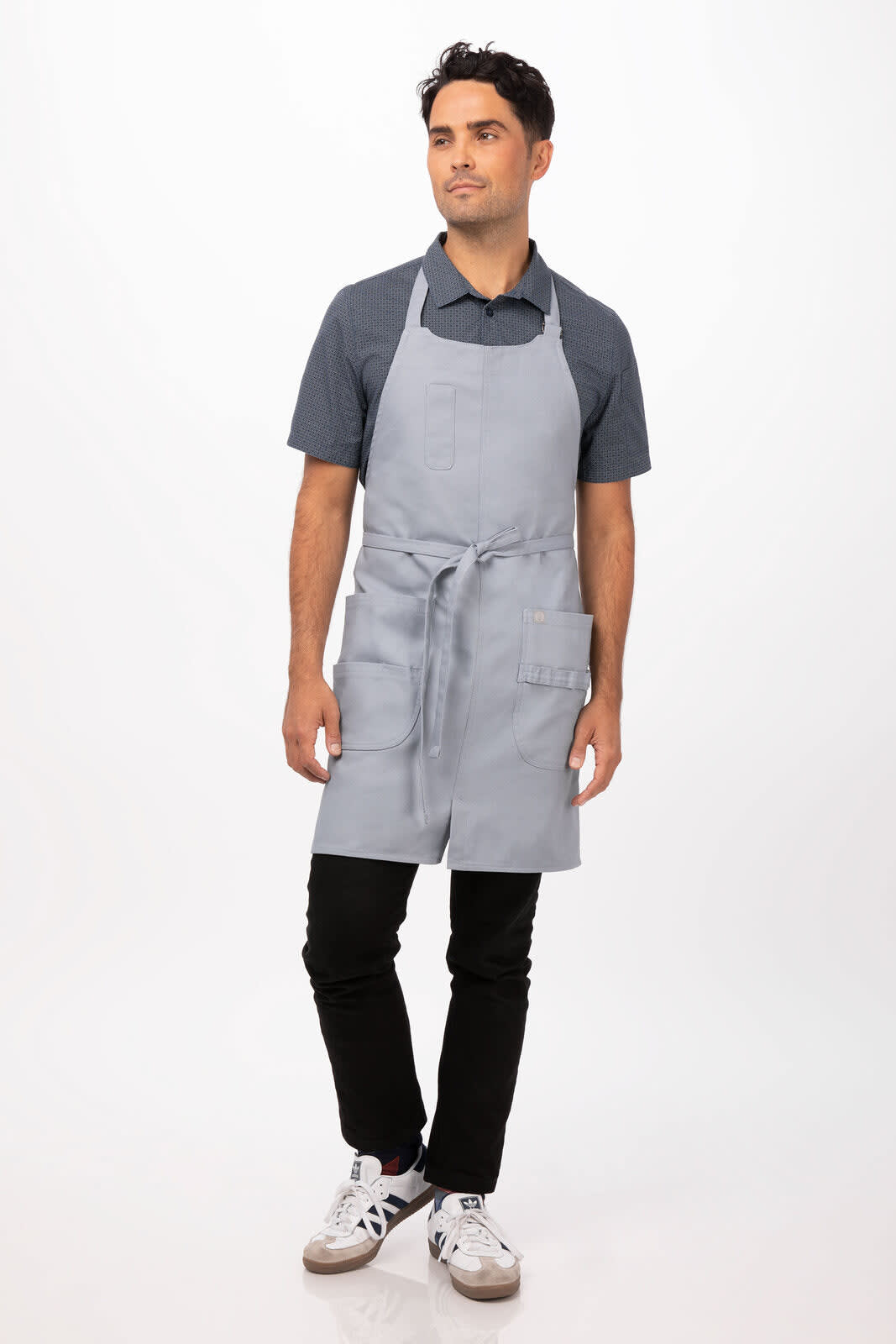 A grey bib apron worn by a man standing against a plain background, featuring a front pocket and ties.