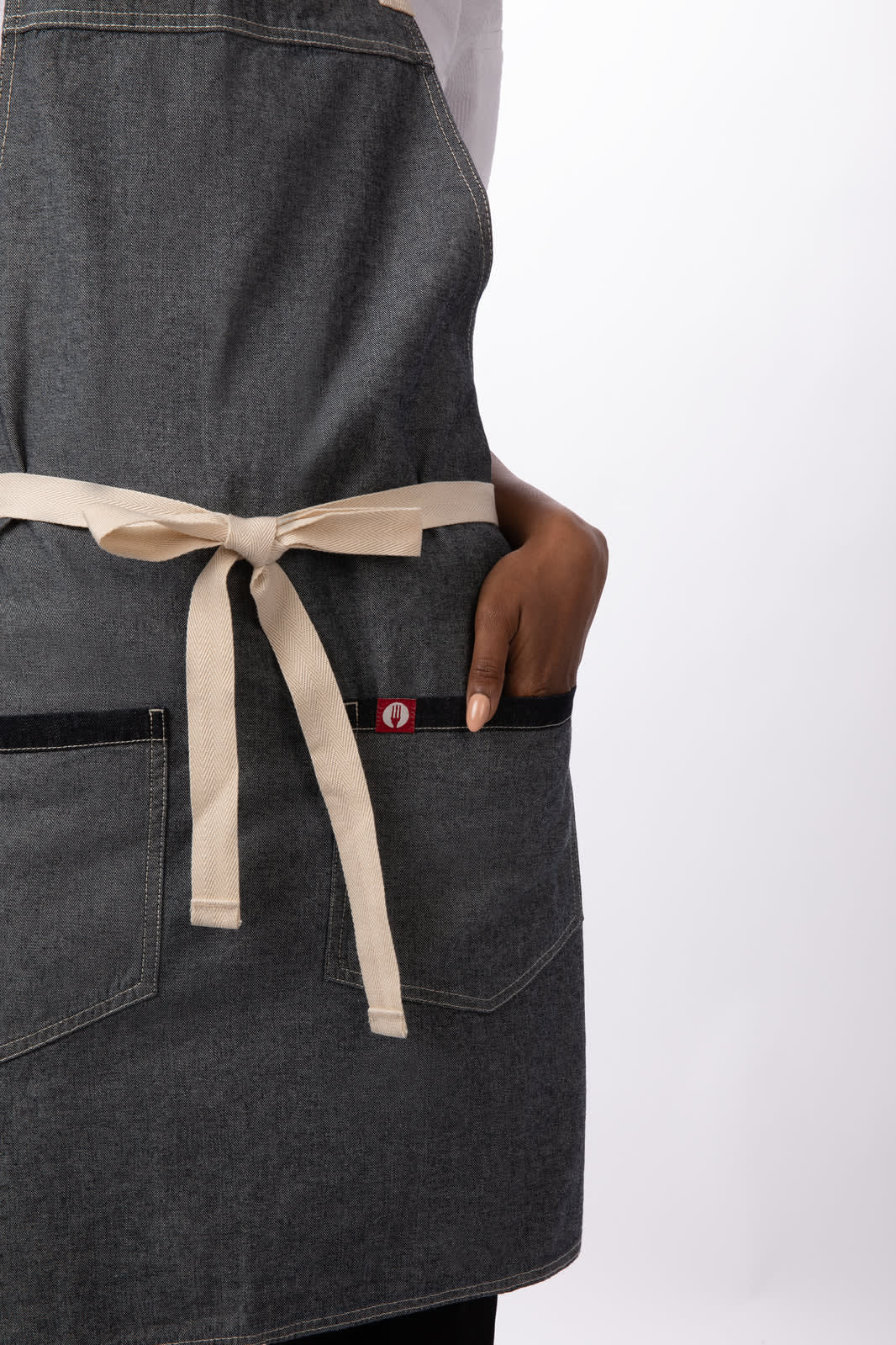 A grey bib apron with a beige tie and pocket, featuring a small logo.