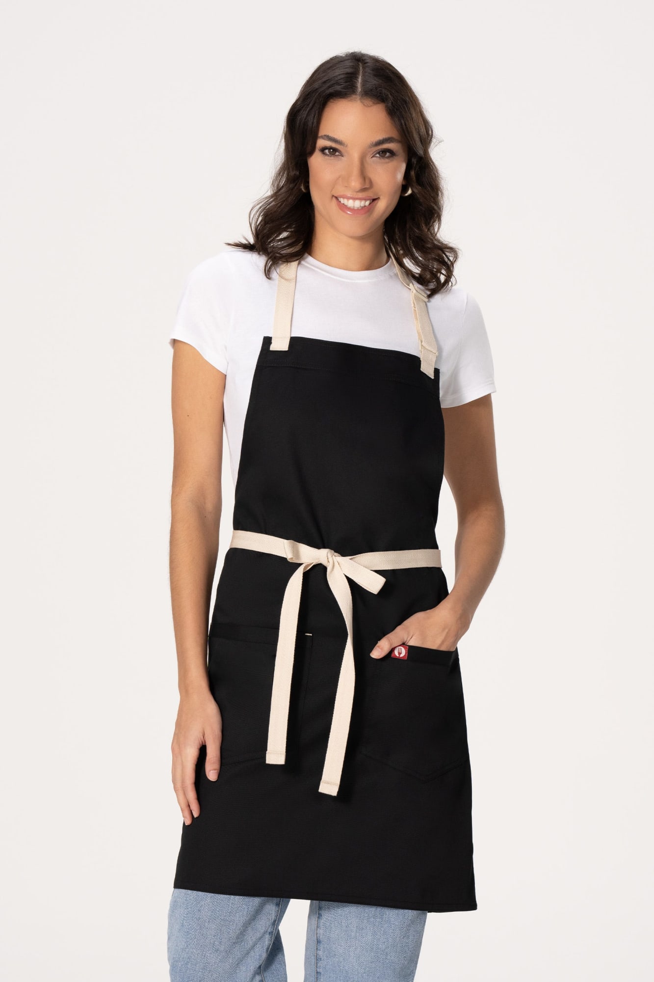 A black bib apron with a beige tie waist, featuring a front pocket, worn by a smiling woman.