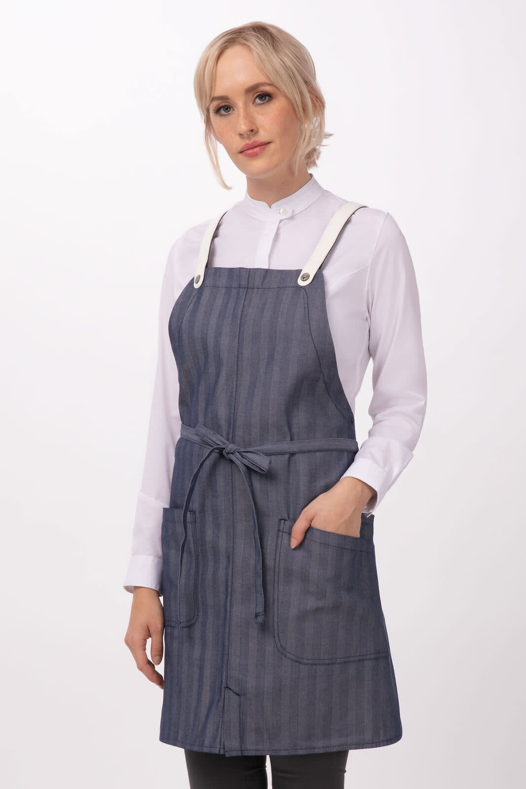A denim blue bib apron with a striped pattern, featuring pockets and adjustable straps, worn by a model.