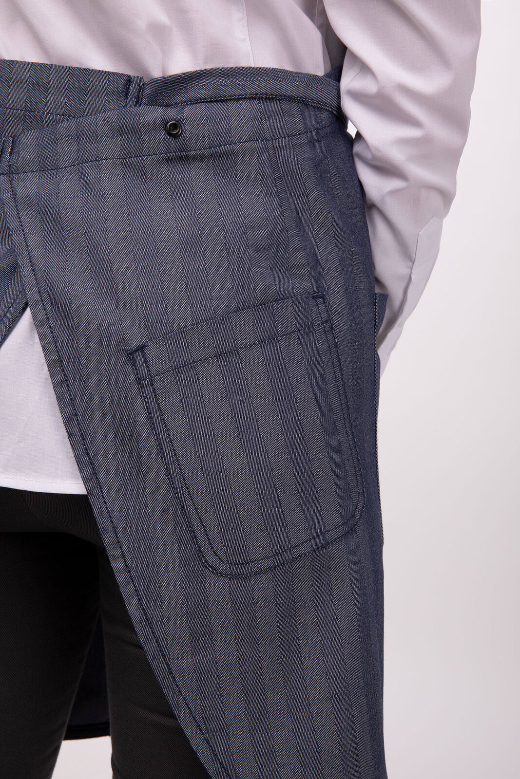 A grey striped bib apron features a side pocket and a button detail, worn over a shirt. It has a sleek design.