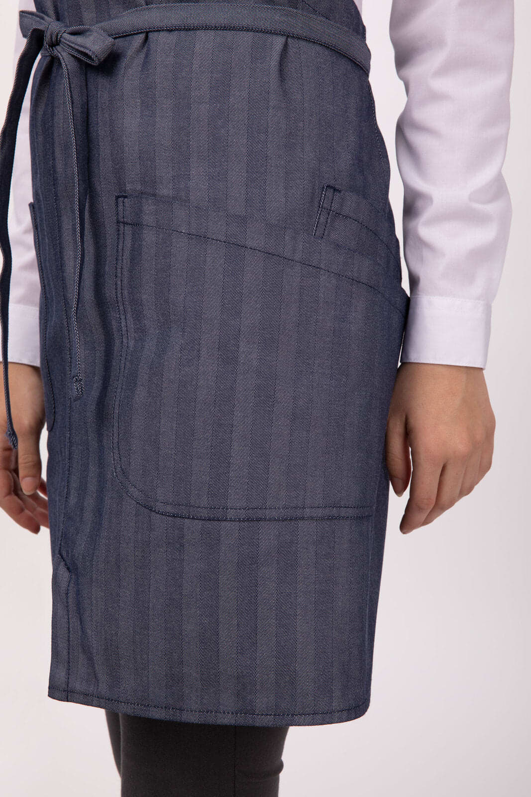 A denim bib apron featuring a front pocket and a tie at the waist. The apron has a subtle striped pattern.