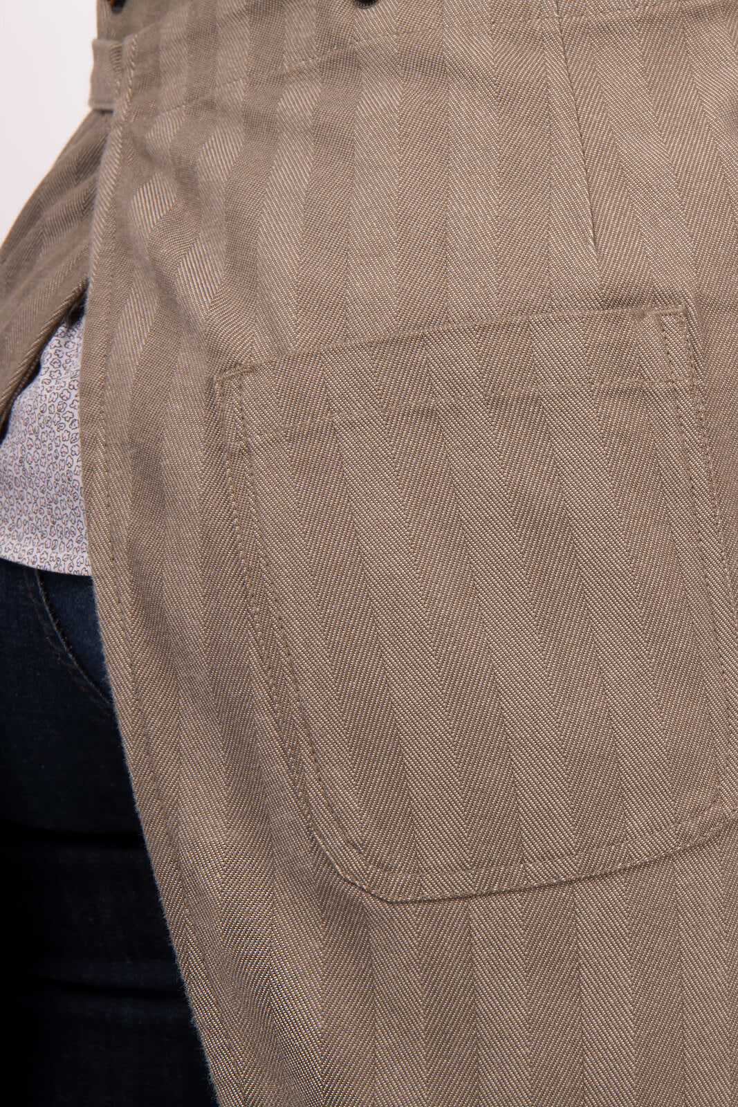 A close-up of a beige striped apron featuring a pocket, showcasing its fabric texture and design.