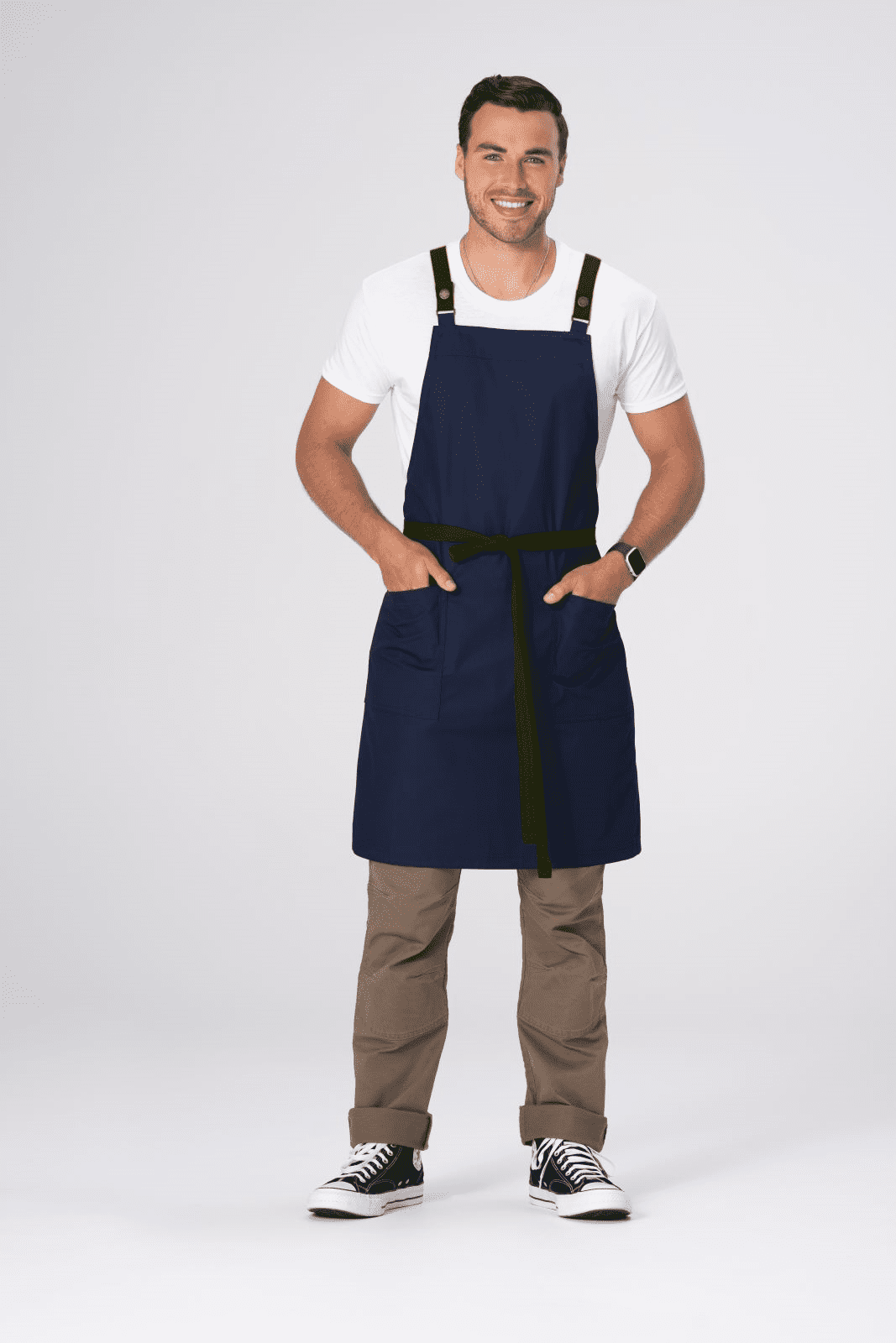 A man wearing a navy blue cross back apron with front pockets and a black tie waist.