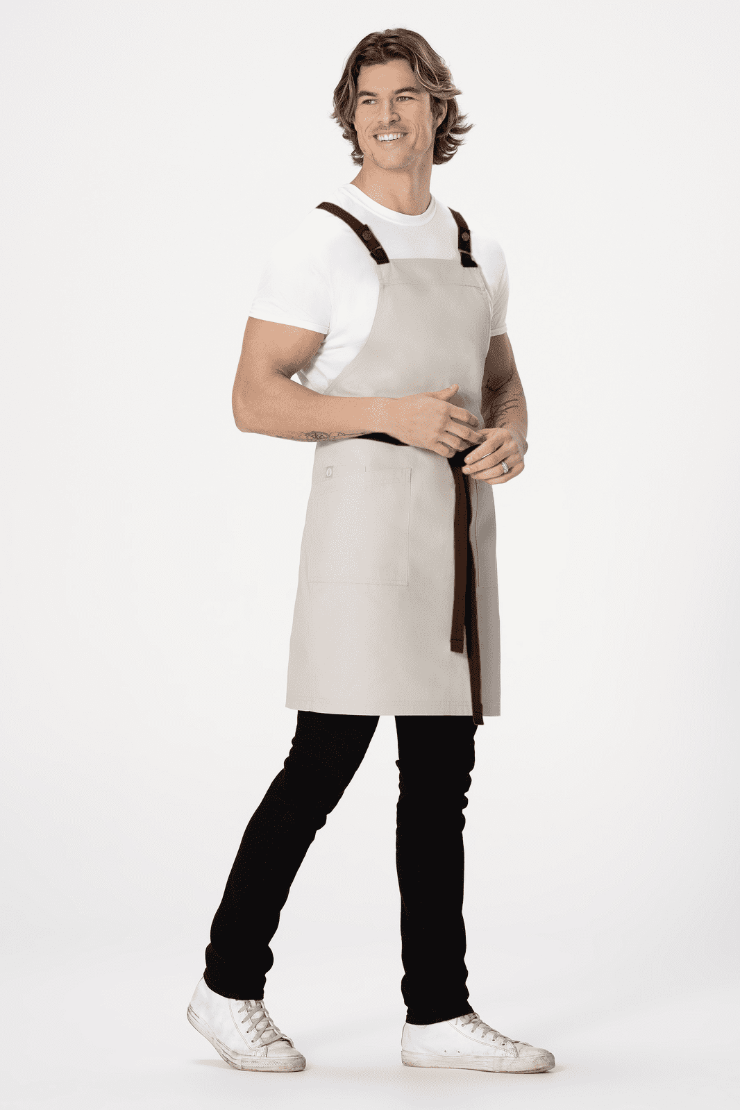 A light grey Cross Back Apron worn by a model, featuring black straps and a stylish design.