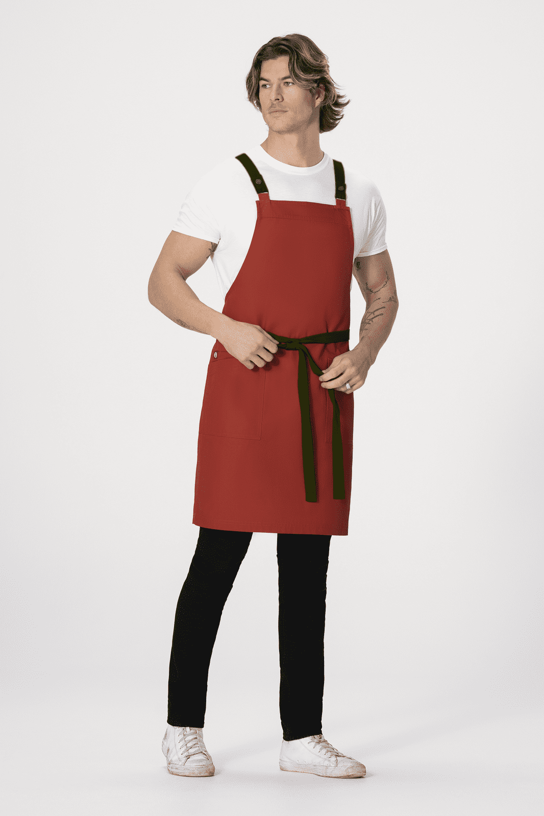 A man wearing a red Lockharte Cross Back Apron with black straps and a tied waist. The background is plain white.