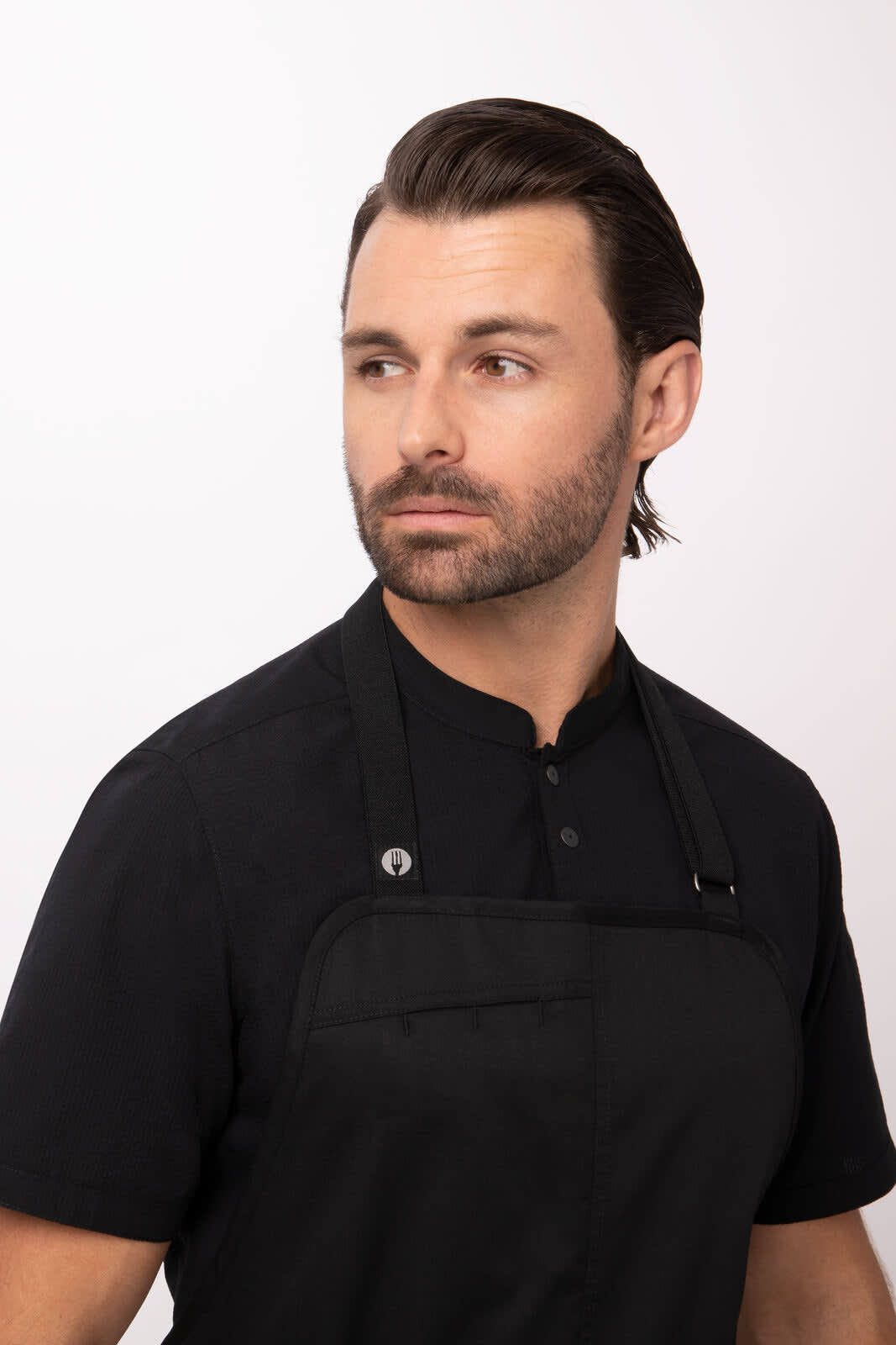 A black Brio Chef Bib Apron worn over a dark shirt by a model, featuring a front pocket and adjustable straps.