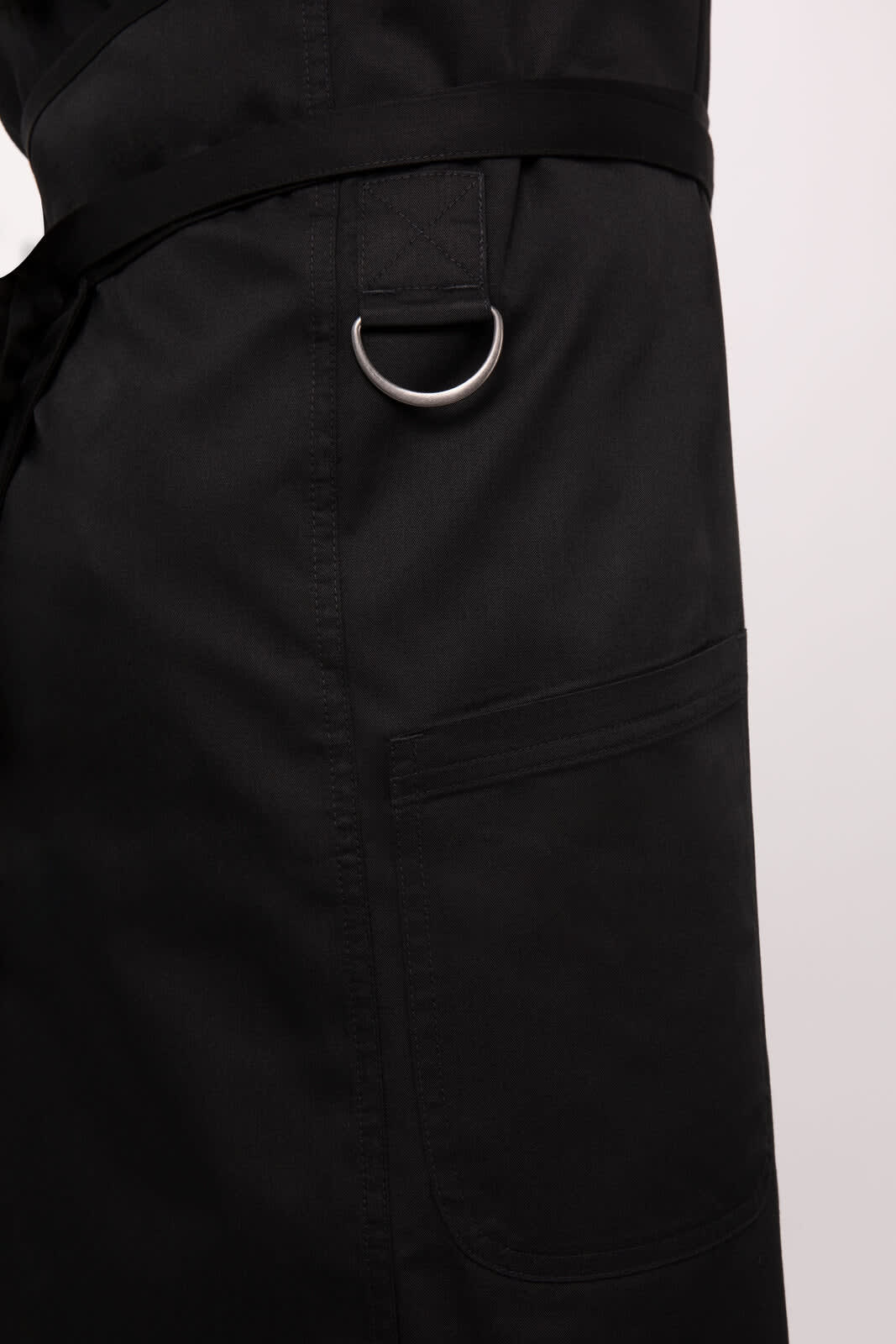 A black bib apron featuring a side pocket and a metal D-ring for tool attachment.