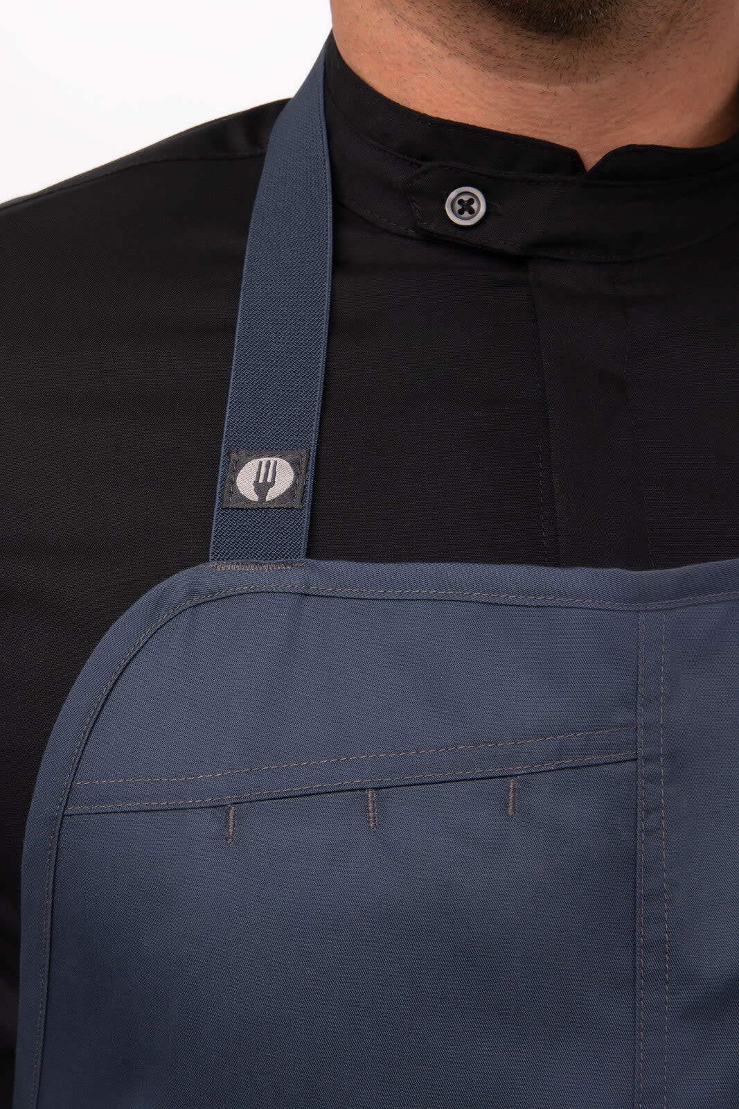 A dark navy bib apron with a logo and a pocket, worn over a black shirt.