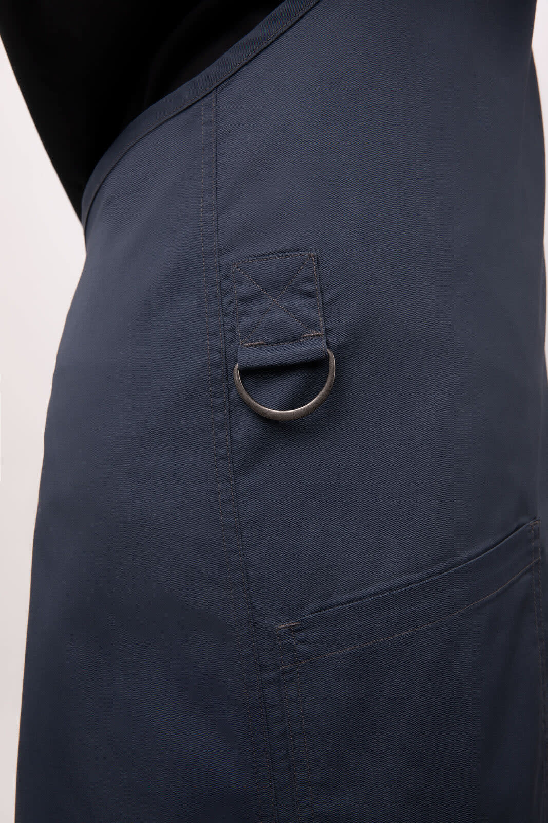 A navy blue bib apron featuring a pocket with a metal ring and a sleek design.
