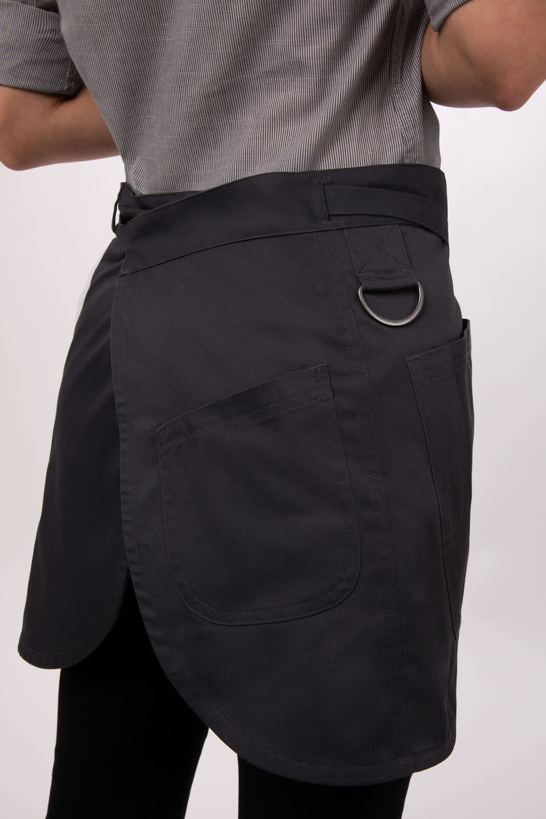 A black half bistro apron featuring a pocket and a metal ring for holding tools. Designed for workwear use.