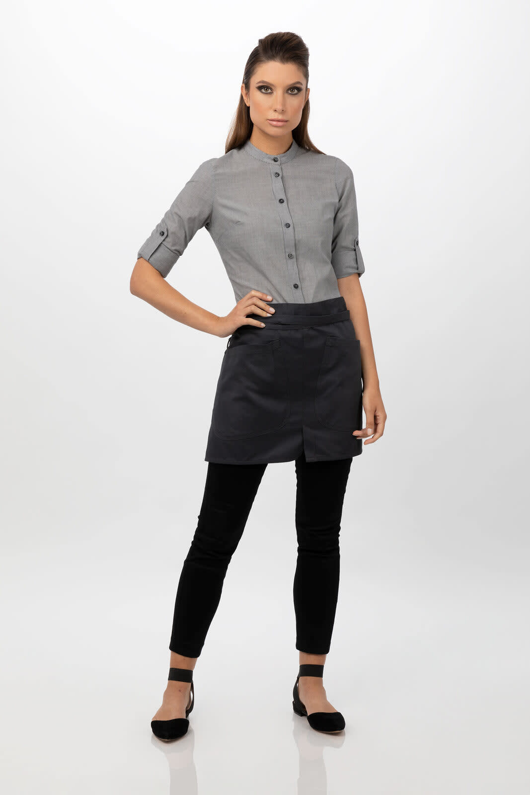 A model wearing a grey shirt and a black half bistro apron, paired with black leggings and flats.