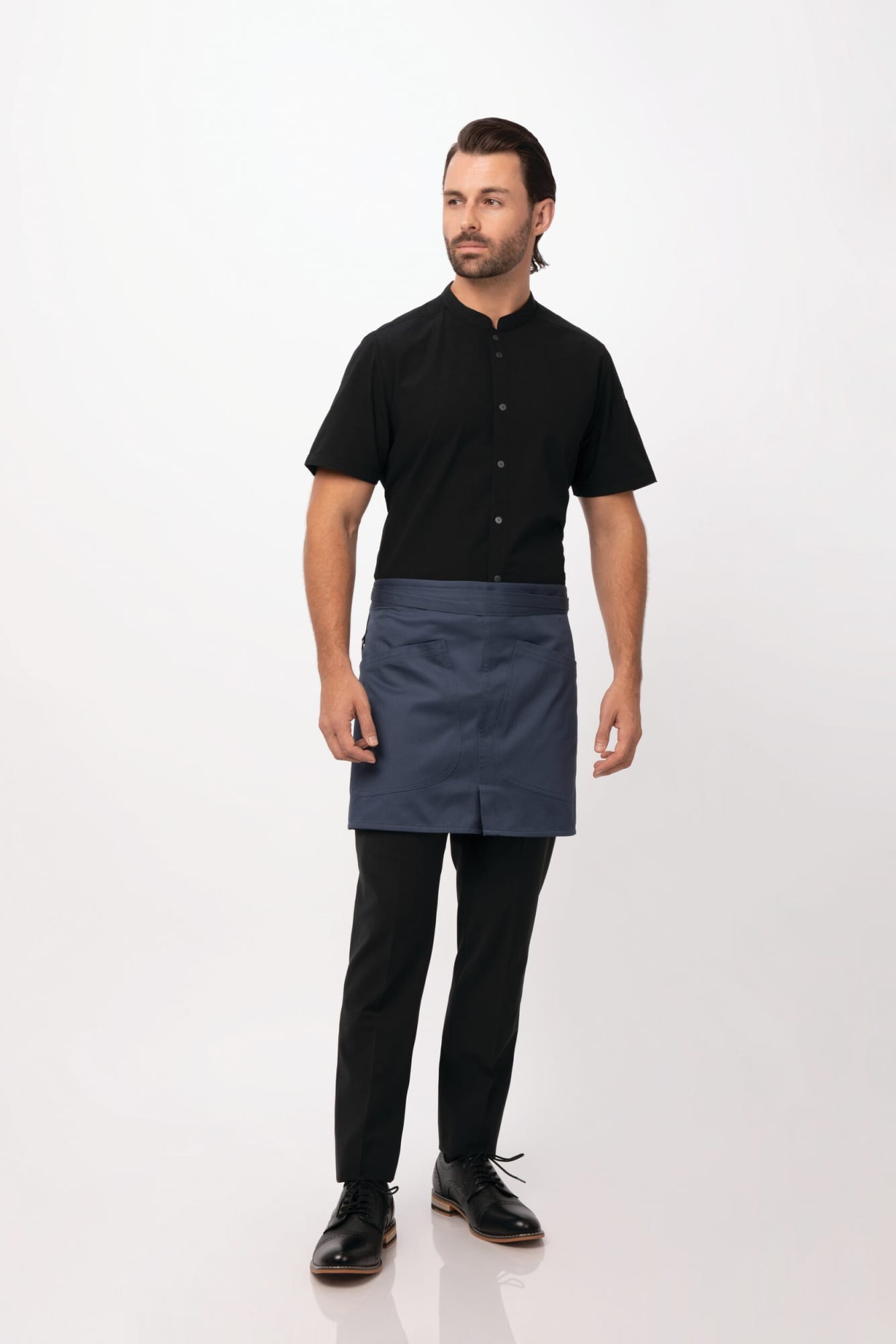 A model wearing a navy bistro apron over a black shirt and black pants, with a logo visible on the apron.