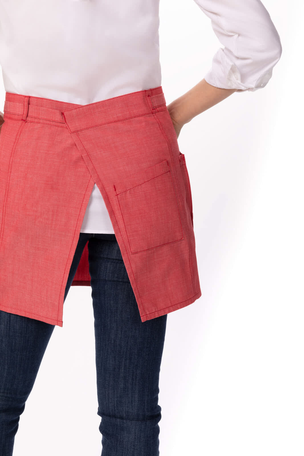 A red half bistro apron with pockets, worn over dark jeans, featuring a back vent and minimal design.