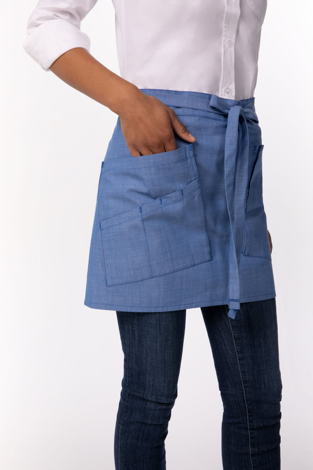 A blue half bistro apron featuring pockets, worn over a white shirt and jeans. The apron includes a logo.