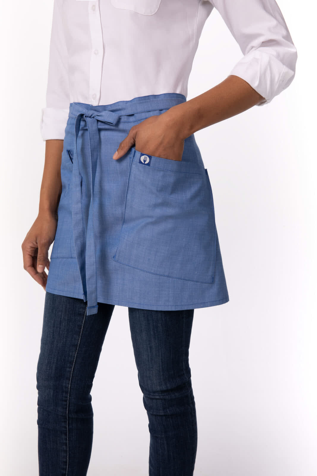 A blue bistro apron with a tie waist and pocket, worn over jeans and a white shirt, featuring a logo.