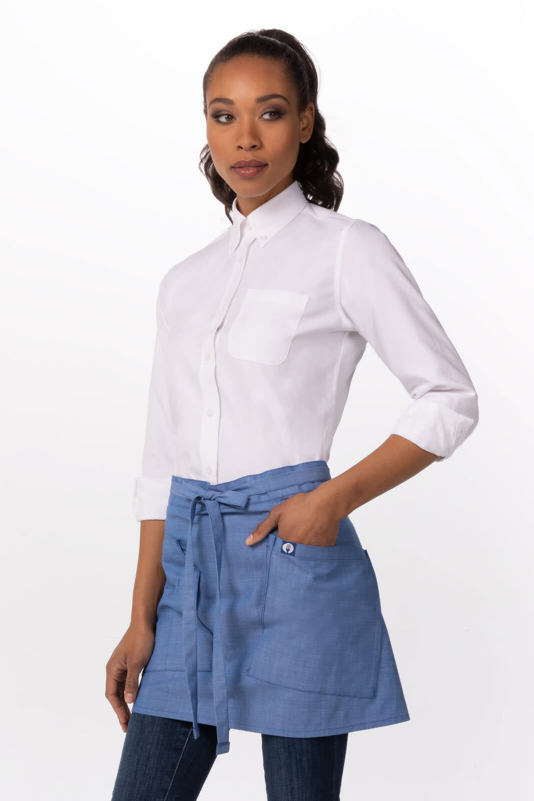A woman models a blue half bistro apron over a white shirt, featuring a pocket and tied at the waist.