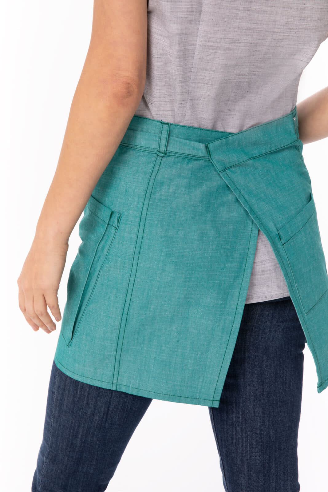 A teal bistro apron with pockets, worn by a person, showcasing a stylish and functional design.