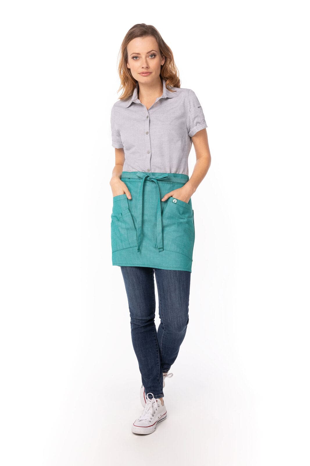 A bistro apron in teal worn over a blue shirt, featuring two front pockets and a tie waist.