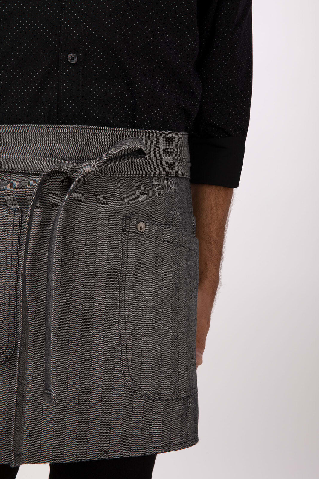 A grey striped half bistro apron with a waist tie and pockets, worn over a black patterned shirt.