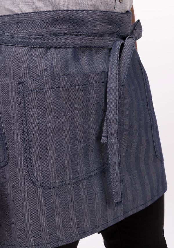 A navy striped bistro apron featuring a tie waist and two front pockets, designed for workwear use.