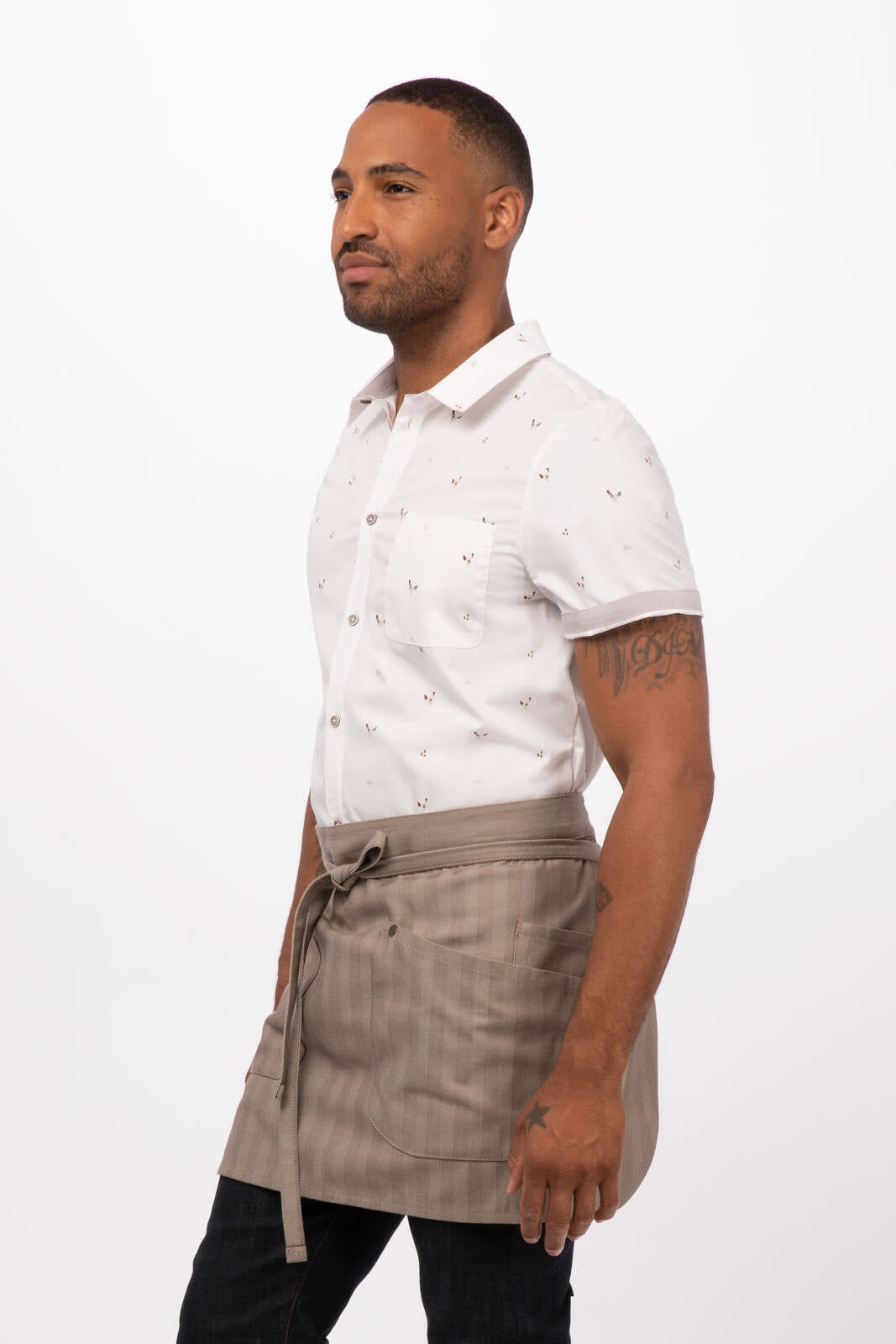 A man wearing a light brown striped bistro apron over a white patterned shirt. The apron features a tying belt.