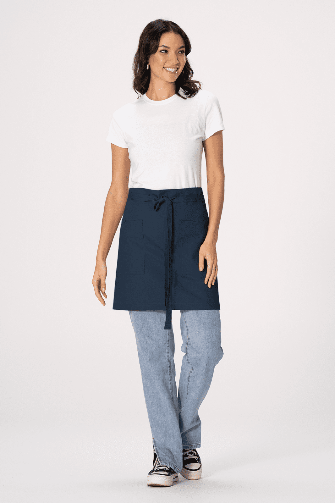 A woman is wearing a navy blue waist apron over casual attire, standing against a light background.