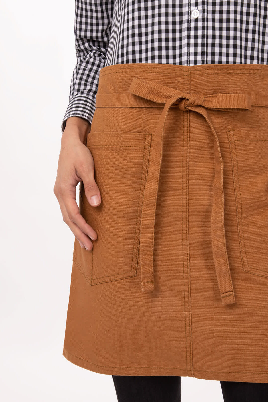 A person holds a Rockford Half Bistro Apron in brown, featuring two front pockets and a tied waistband.