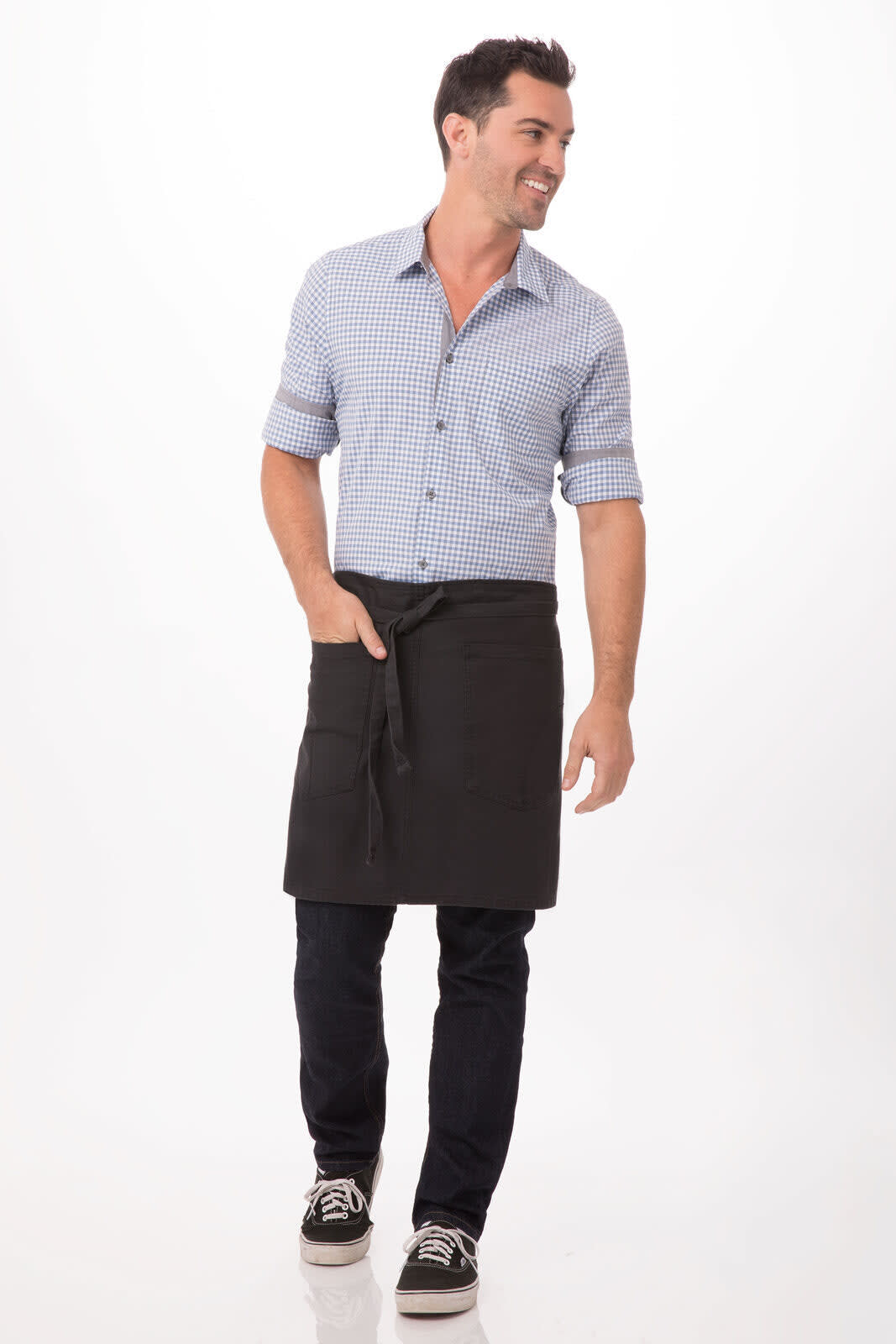 A man wearing a black half bistro apron over a checkered shirt and jeans, with a logo visible on the apron.