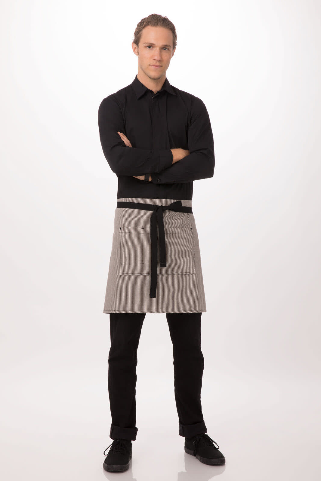 A man stands wearing a grey bistro apron over black attire, featuring pockets and a tied waist.