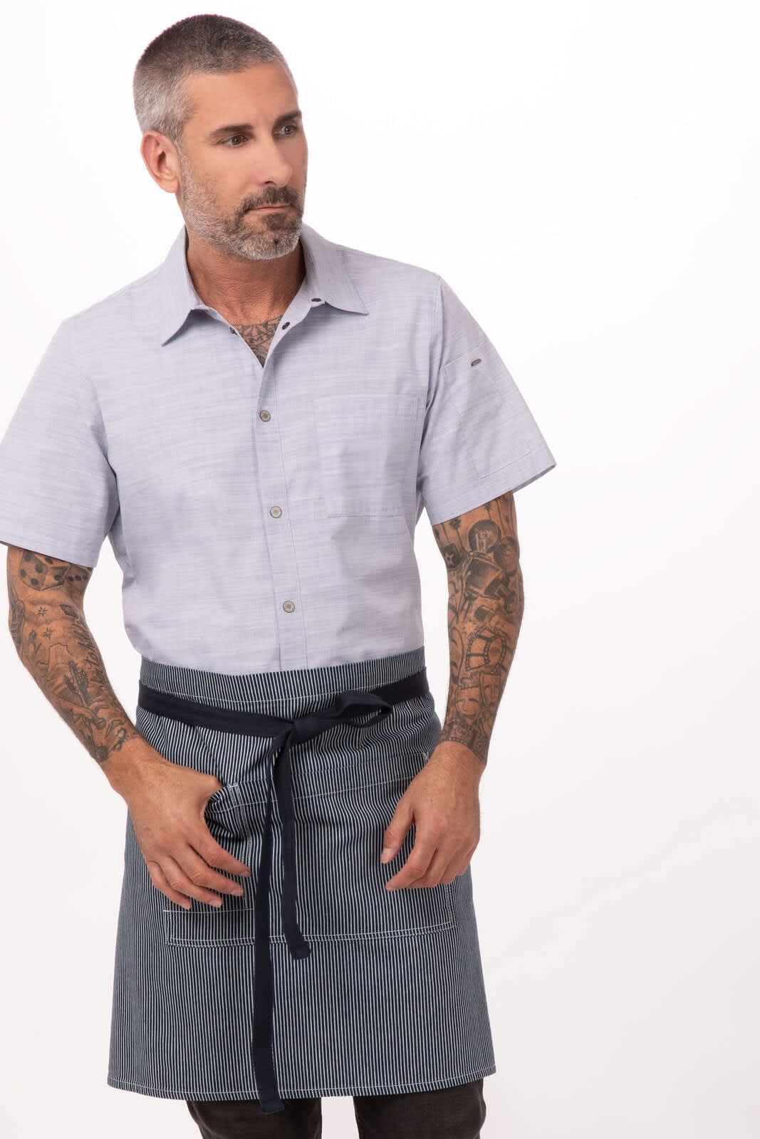 A man in a grey shirt wears a striped blue and white bistro apron with a tie waist and a logo.