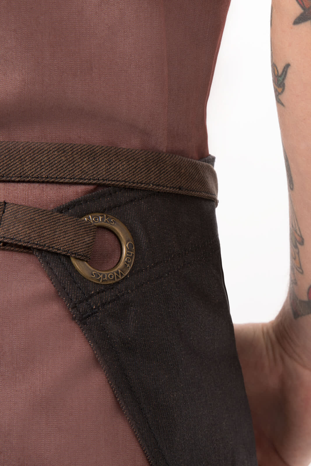 A bistro apron in brown and black with a belt loop detail, featuring a logo.