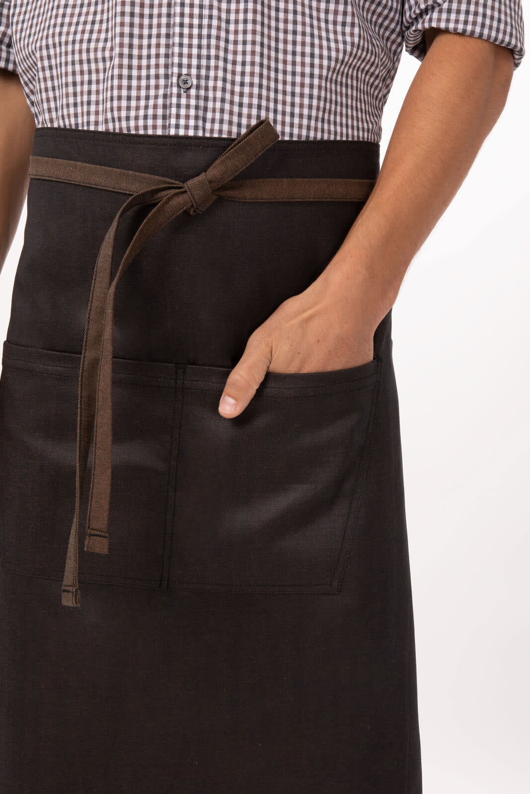 A black apron featuring a front pocket and a brown waist tie, worn by a person in a checked shirt.
