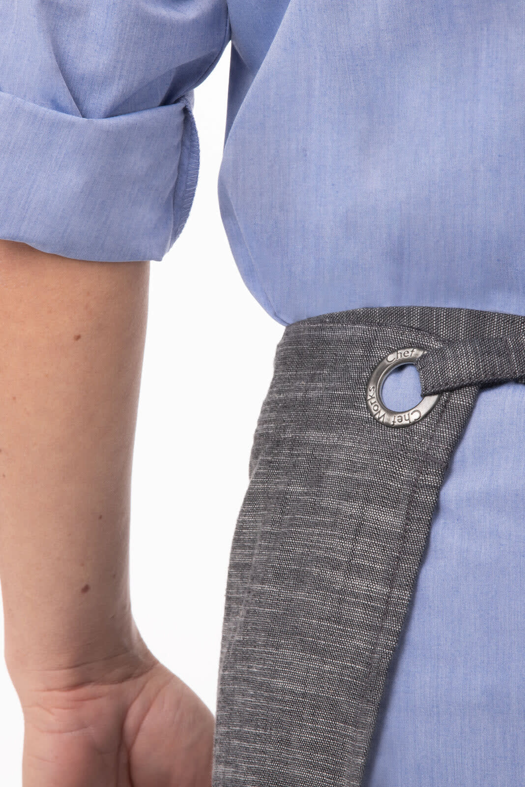 A grey apron with a metal ring detail, worn over a light blue shirt.