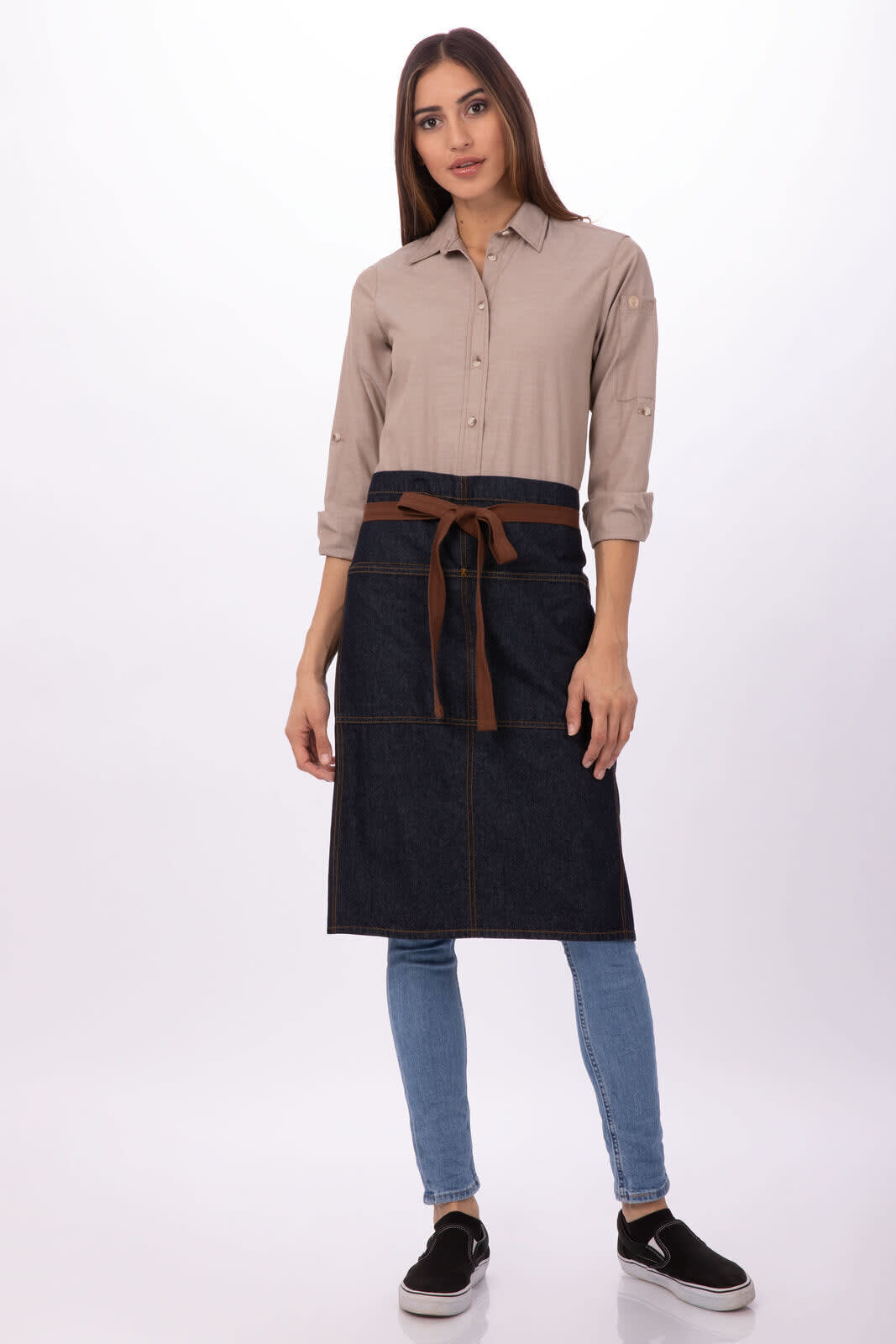 A denim bistro apron in navy with a brown waist tie, worn over a beige shirt and blue jeans. Features branding.