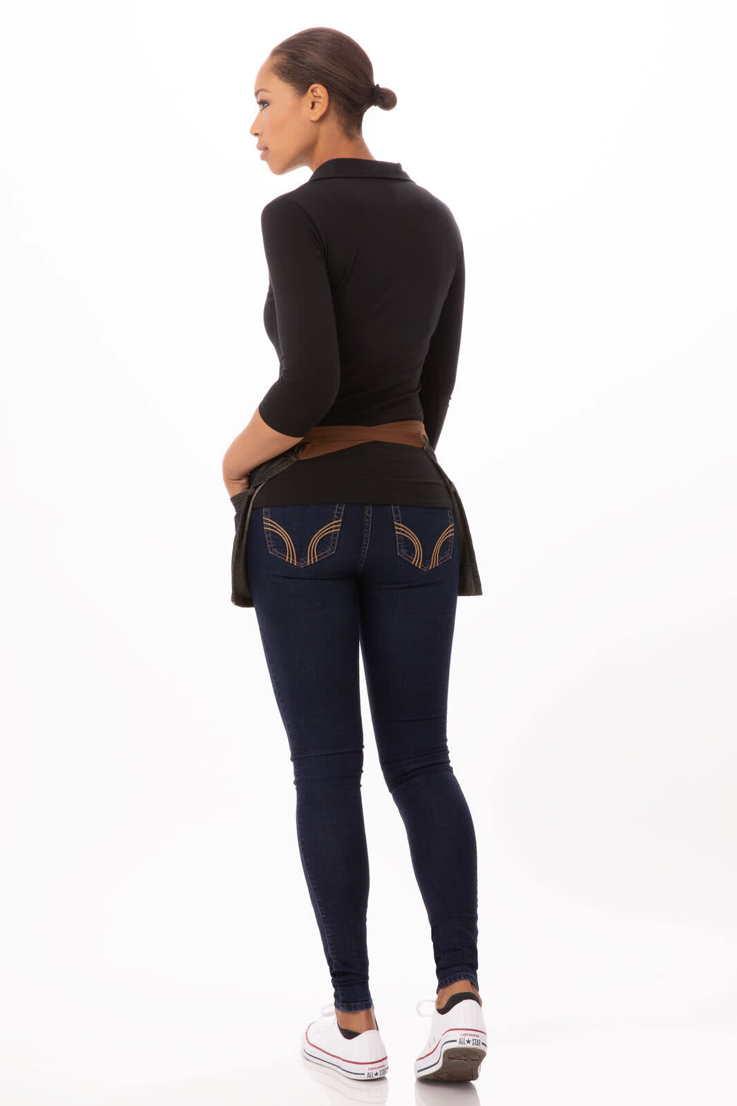 A model wearing a black waist apron over denim jeans, showcasing the back view with a detailed pocket design.