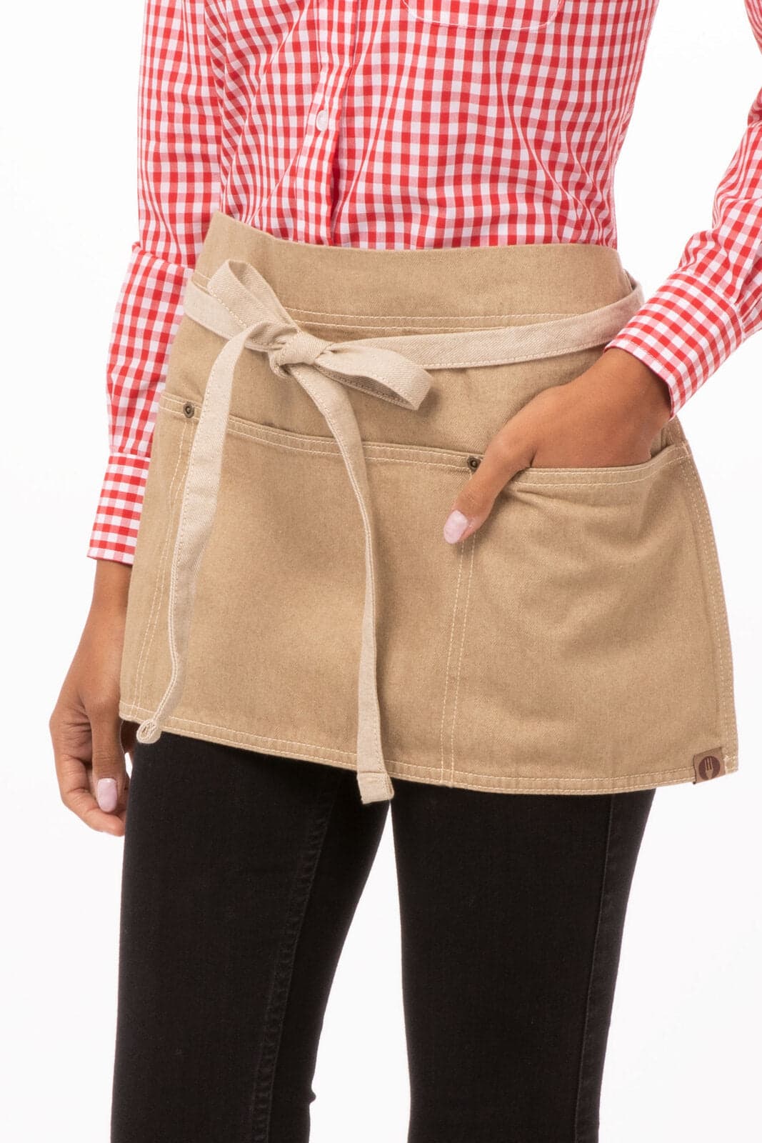 A beige waist apron with two pockets, featuring a tied waist and worn over black pants.