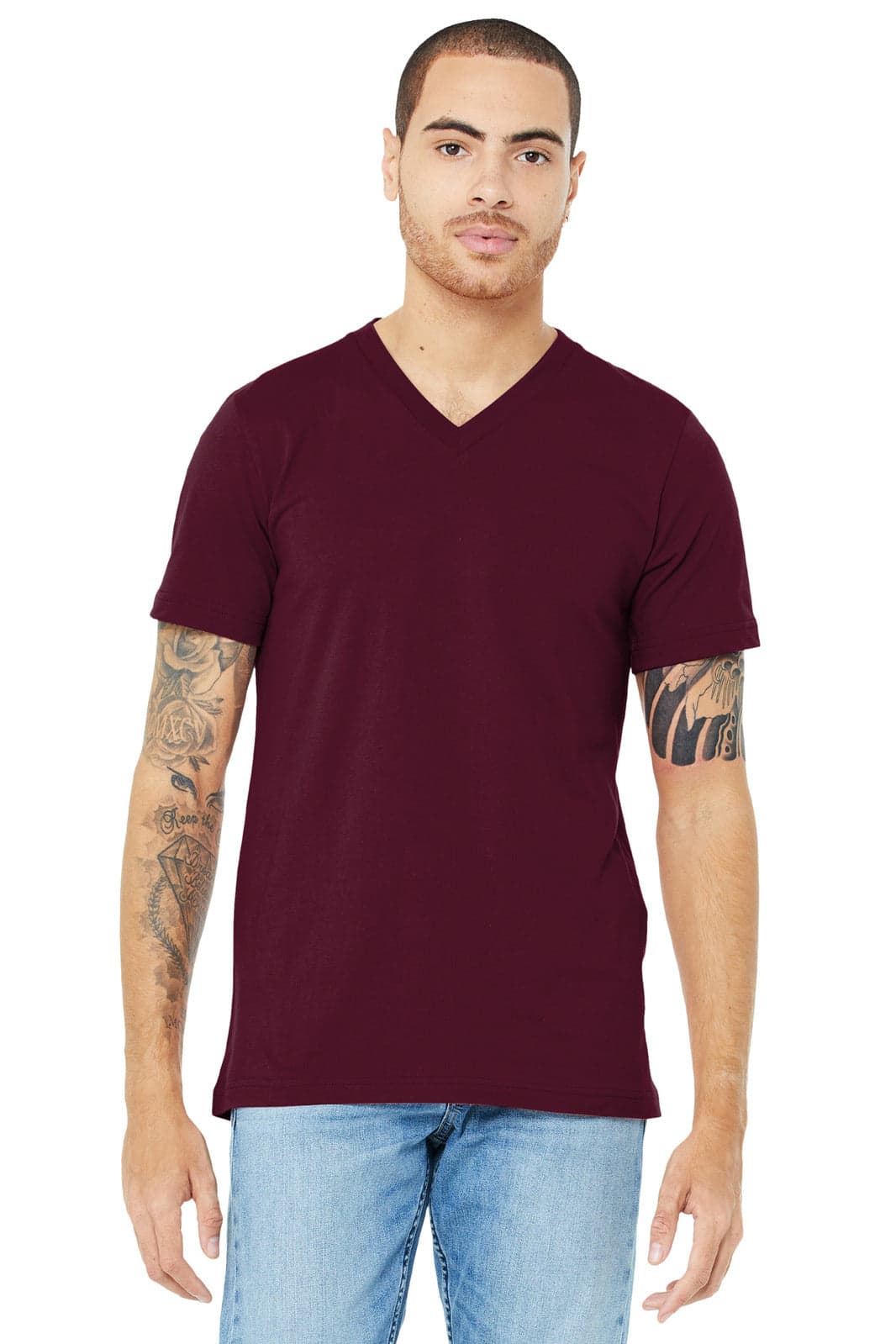 A unisex jersey short sleeve v-neck tee in burgundy, worn by a model with tattoos. The shirt has a logo.