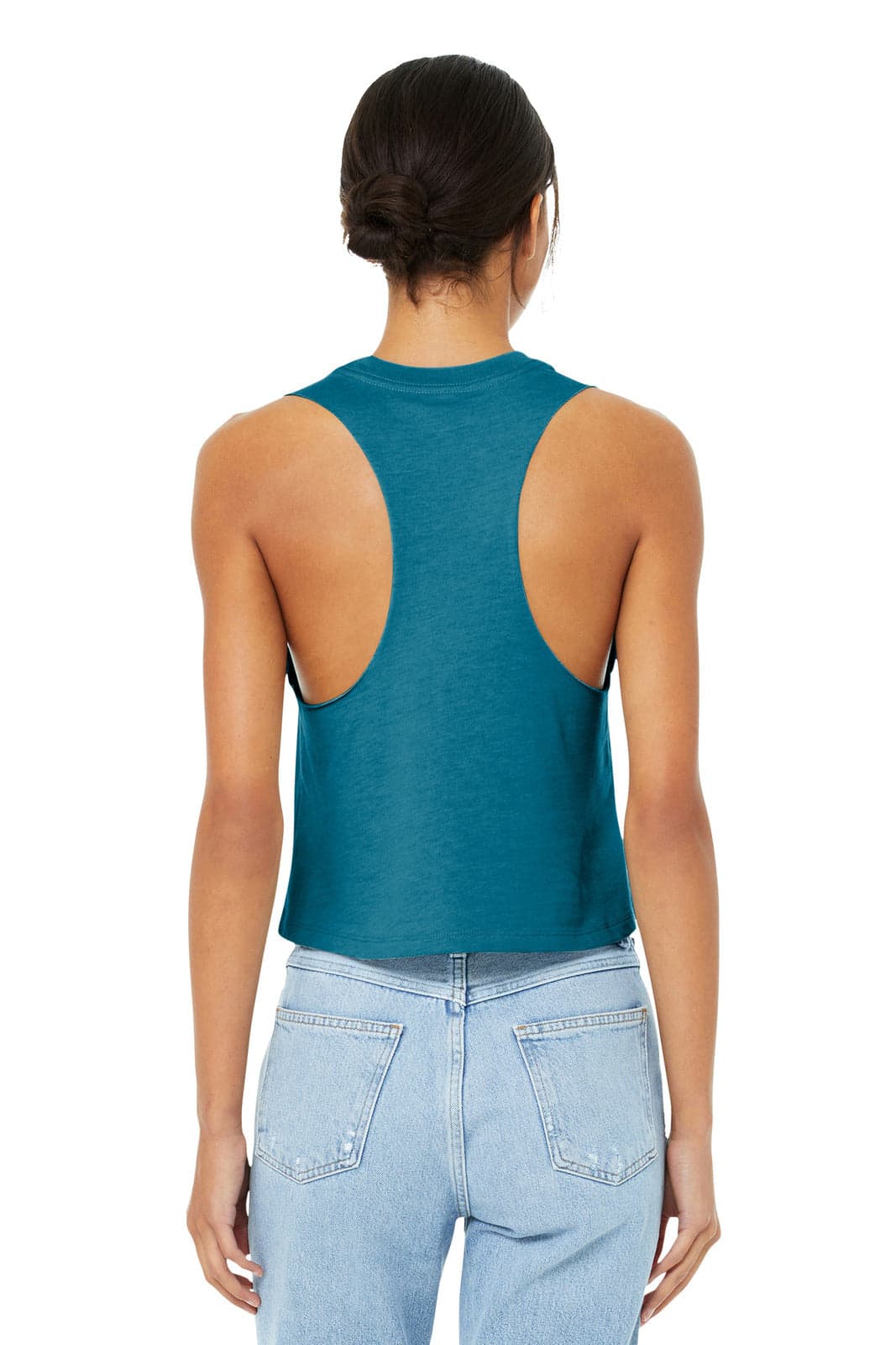 A teal women's racerback cropped tank top with open back design, paired with light denim jeans. Features a logo.