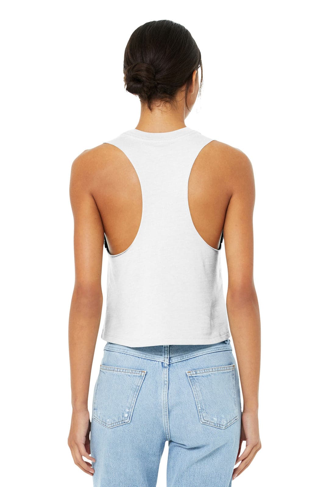 A women's racerback cropped tank in white, featuring a back cut-out design. The model pairs it with light blue jeans.